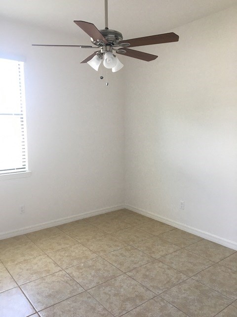 an empty room with a ceiling fan and a tiled floor