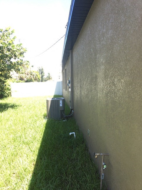 the side of a house with an air conditioning unit in the grass