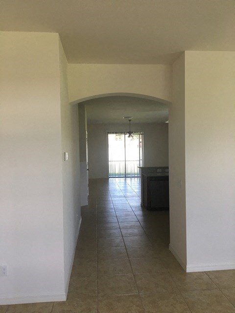 an empty living room and hallway with a tiled floor
