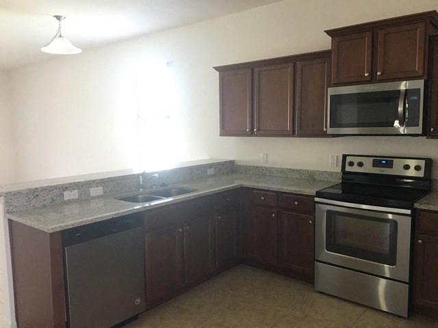 an empty kitchen with stainless steel appliances and wooden cabinets