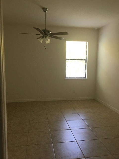 an empty room with a ceiling fan and tiled floor