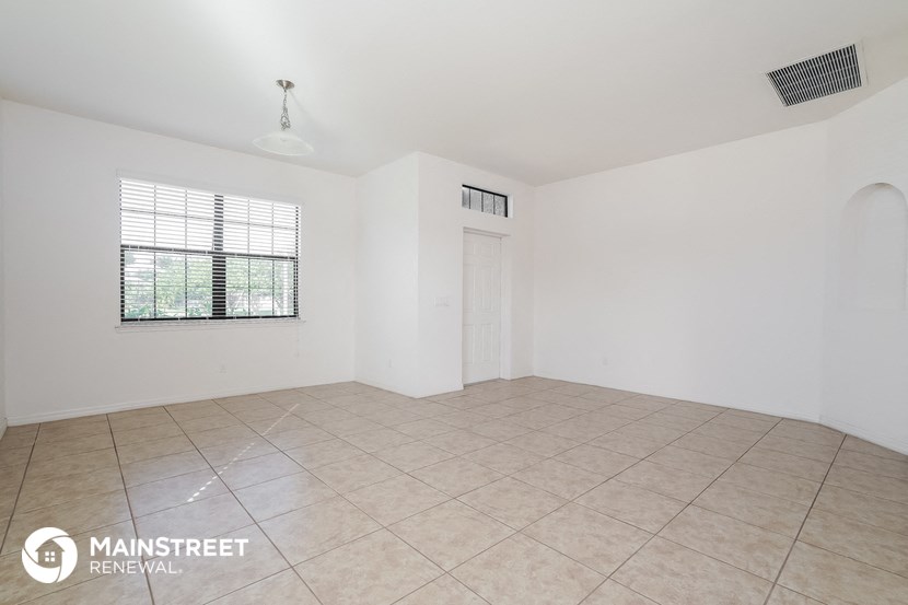 an empty living room with a tile floor and a window