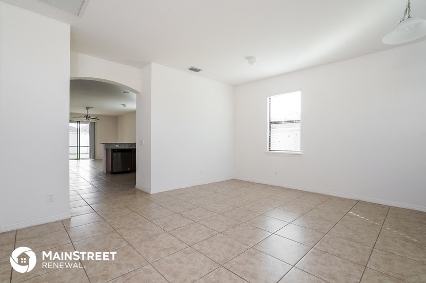 an empty living room with white walls and a tile floor