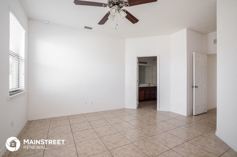 an empty living room with a ceiling fan and a tiled floor