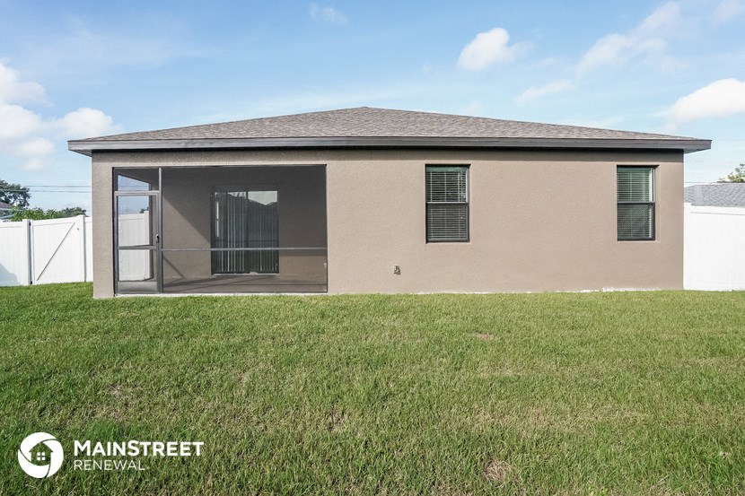 a small tan house with a grassy yard