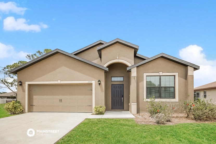 a beige house with a garage door and a driveway