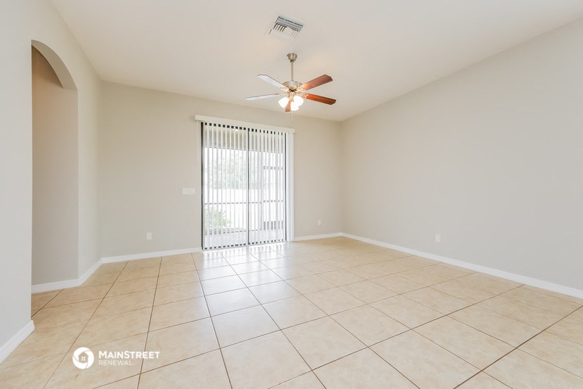 an empty living room with a ceiling fan and tile flooring
