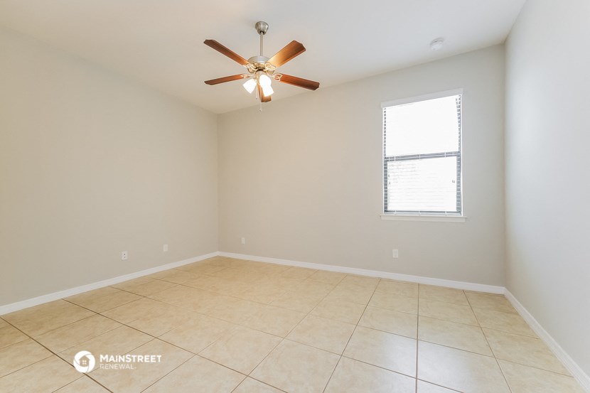 the spacious living room with ceiling fan and tiled floors