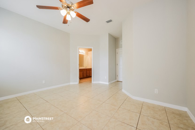an empty living room with a ceiling fan and tiled floor