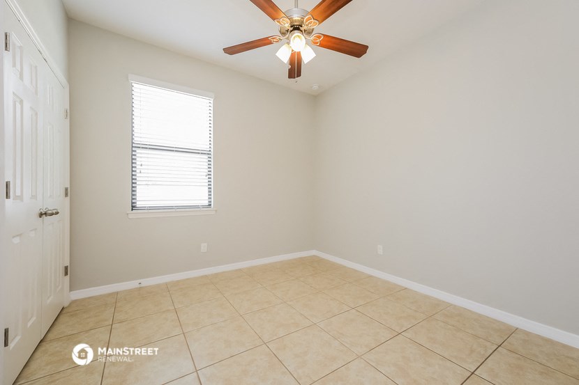 an empty room with a ceiling fan and a tiled floor