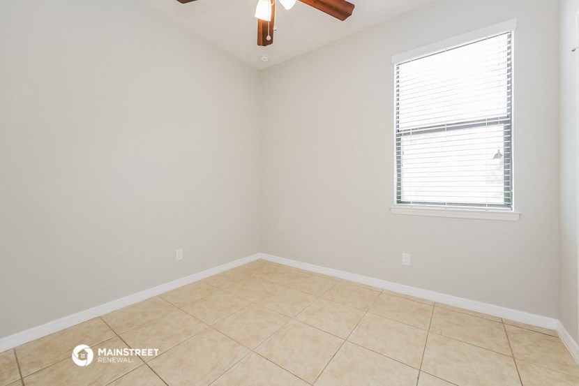 an empty room with a window and a ceiling fan