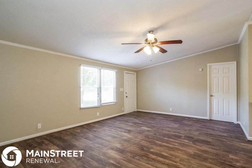 an empty living room with a ceiling fan and a window