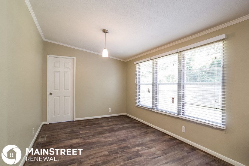 an empty living room with a large window and a white door