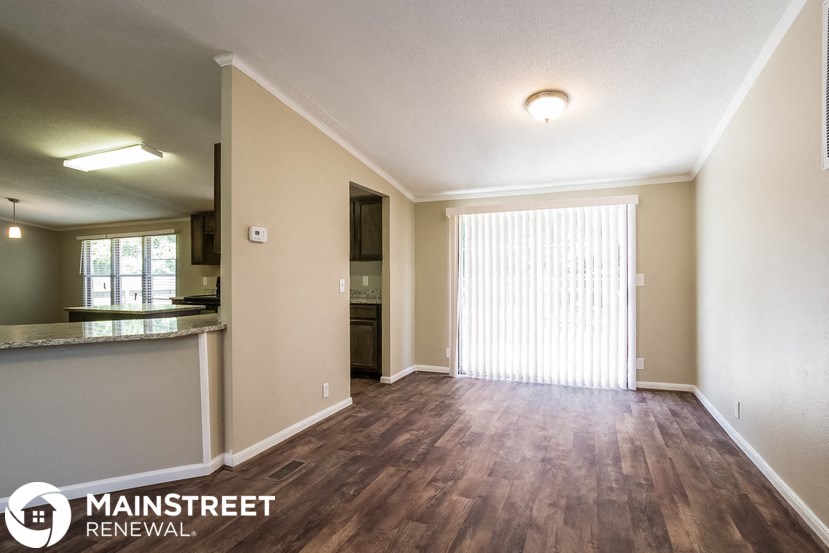 the living room and dining room of an apartment with wood flooring