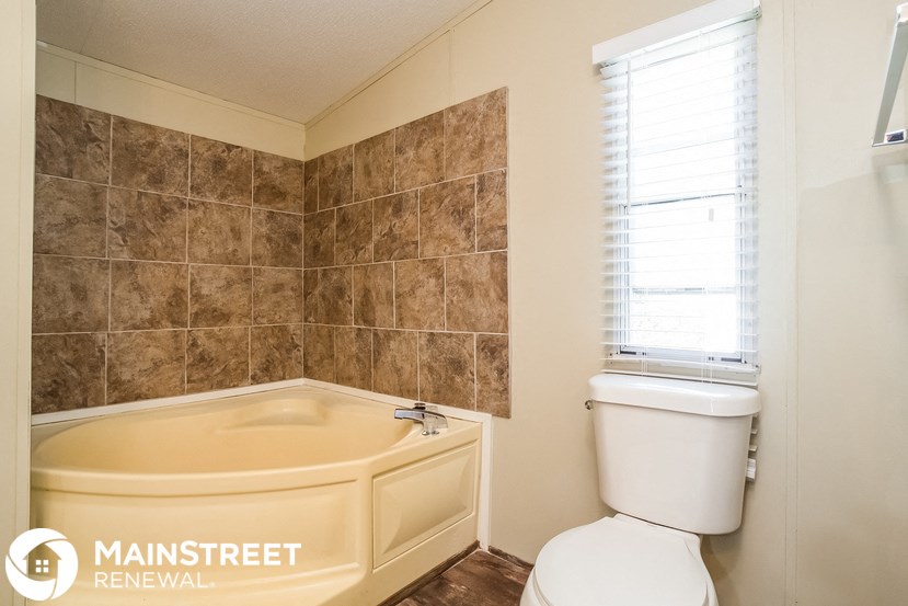 a bathroom with a tub and a toilet and a window