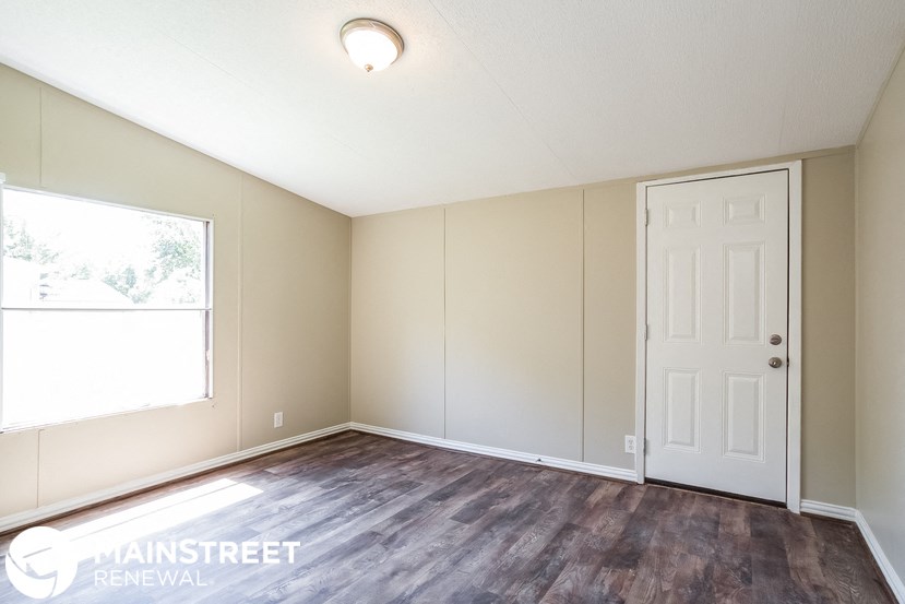 an empty room with a white door and a window