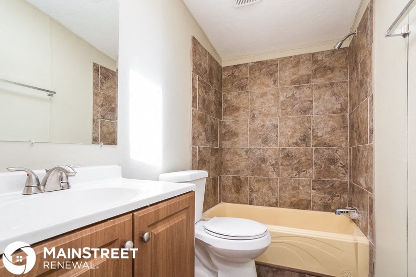 a bathroom with a toilet sink and tub and a mirror