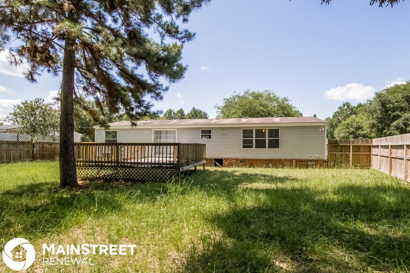 the exterior of a mobile home with a fenced in yard and a tree
