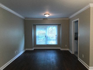 a empty living room with a large window and wooden floors