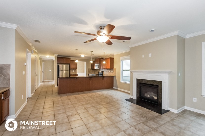 a large living room with a fireplace and a ceiling fan