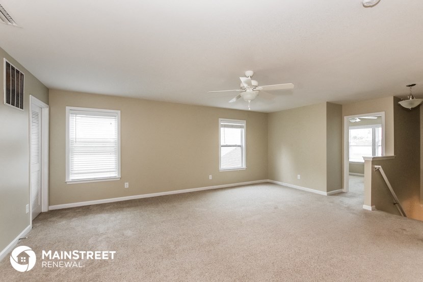 the living room of an empty house with a ceiling fan