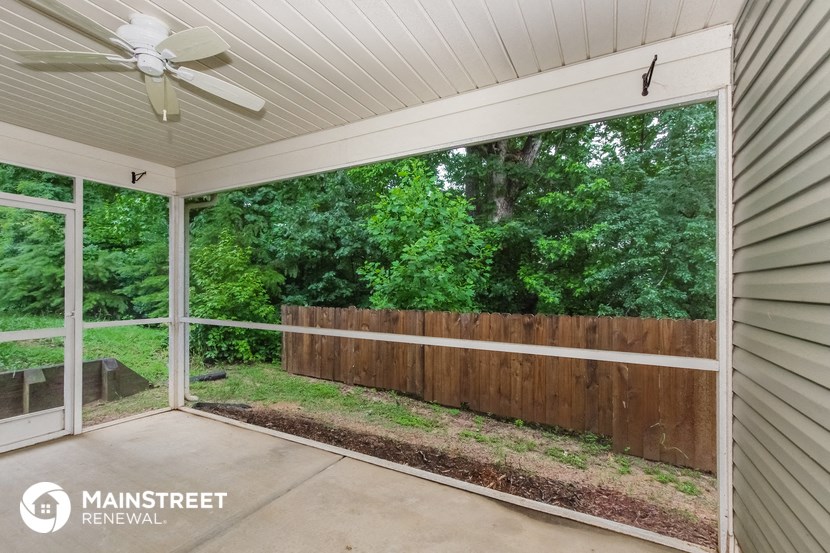 a covered porch with a wood fence and a view of the woods
