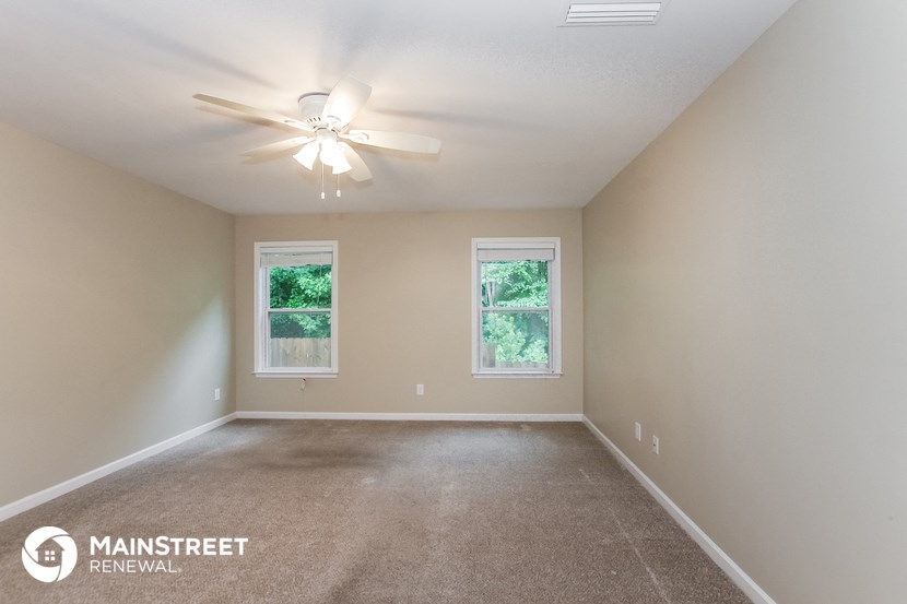 the spacious living room with ceiling fan and carpeting