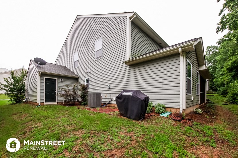 the back of a house with a yard and a trash can