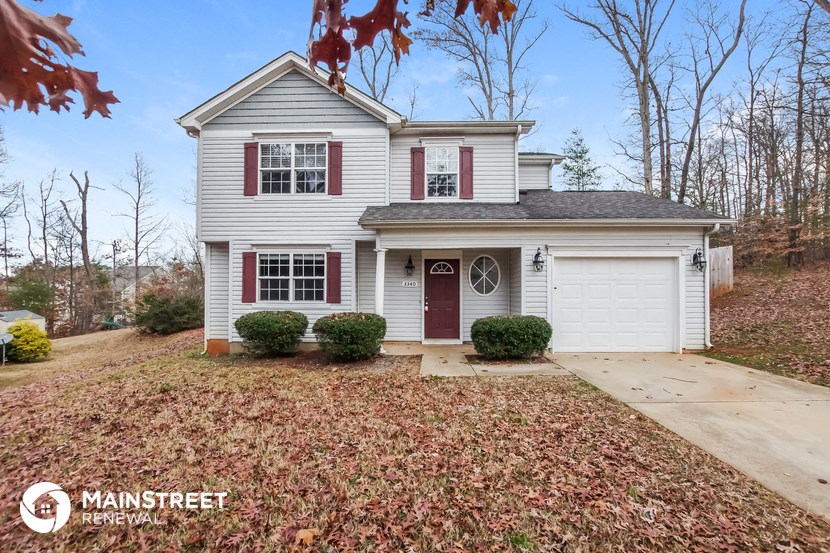 a white house with red shutters and a driveway