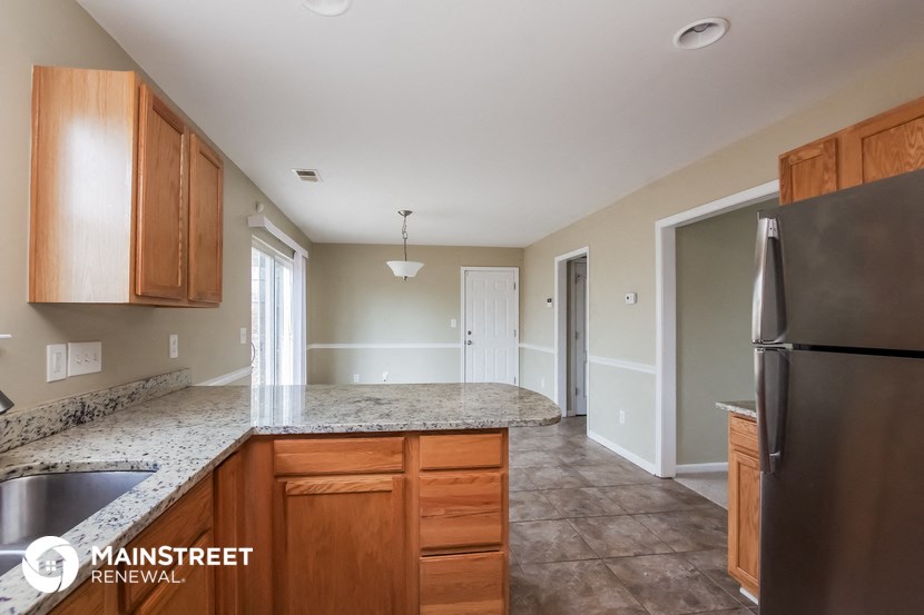 a kitchen with wood cabinets and granite counter tops and a stainless steel refrigerator