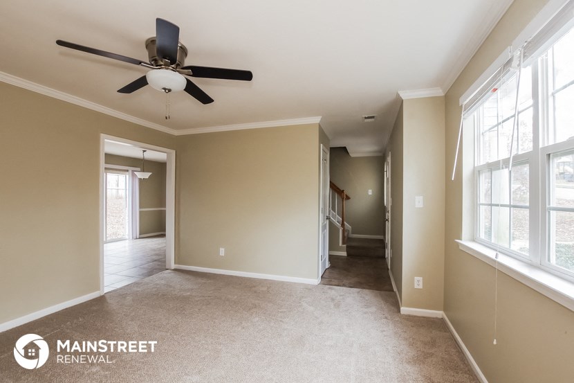 a empty living room with a ceiling fan and a hallway