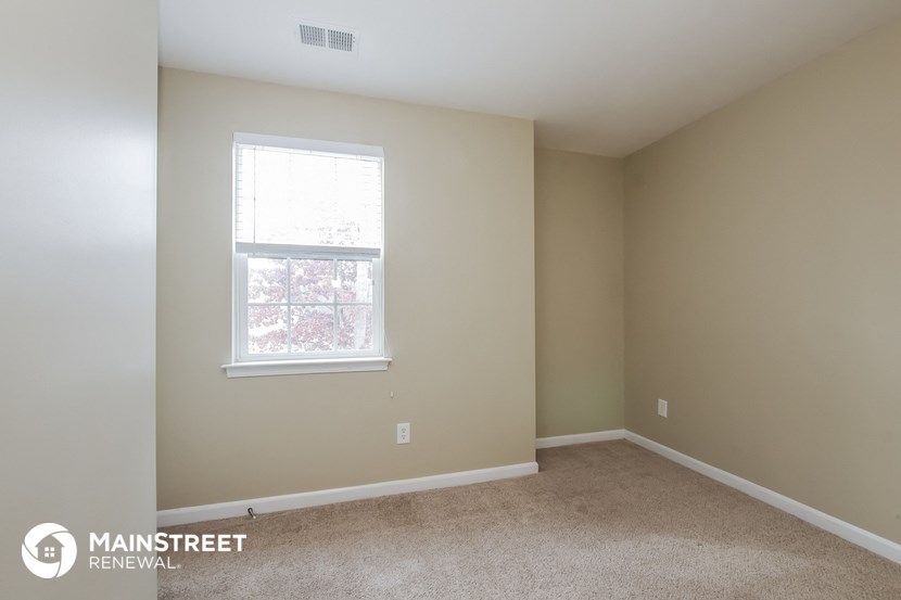 a bedroom with a window and a carpeted floor