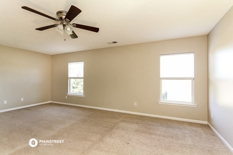 the spacious living room with carpet and a ceiling fan