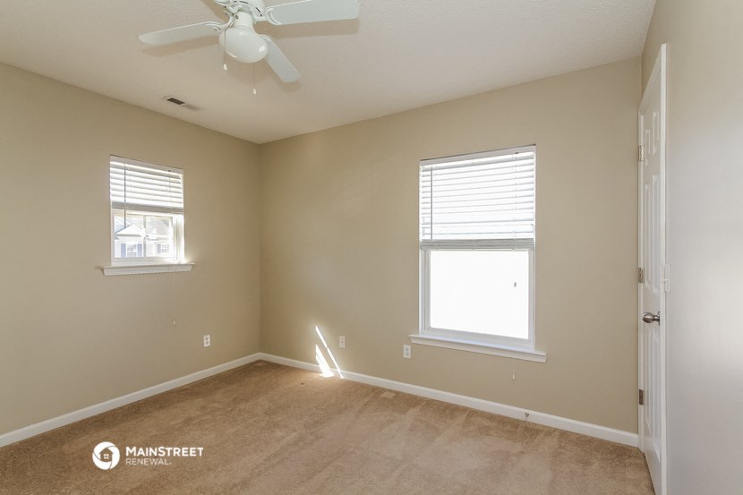 an empty room with a ceiling fan and two windows