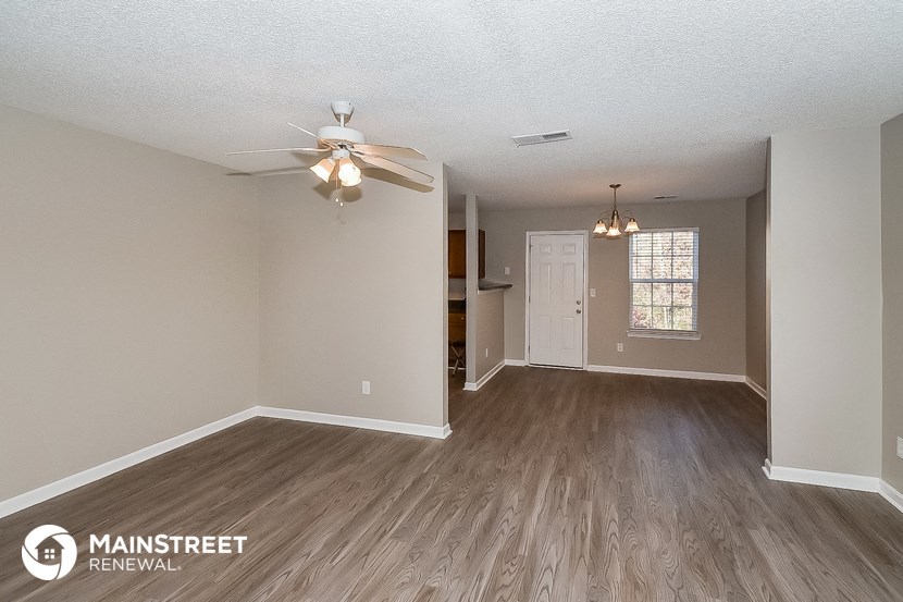 the living room of an empty house with a ceiling fan