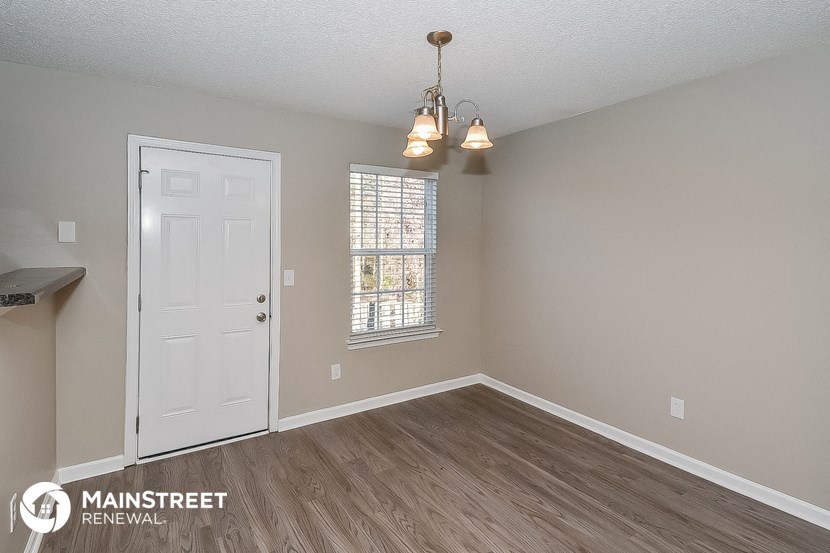 the living room of a house with a white door and wood floors