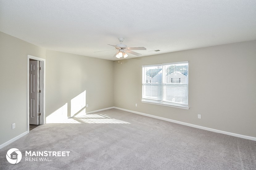 an empty living room with a ceiling fan and a window