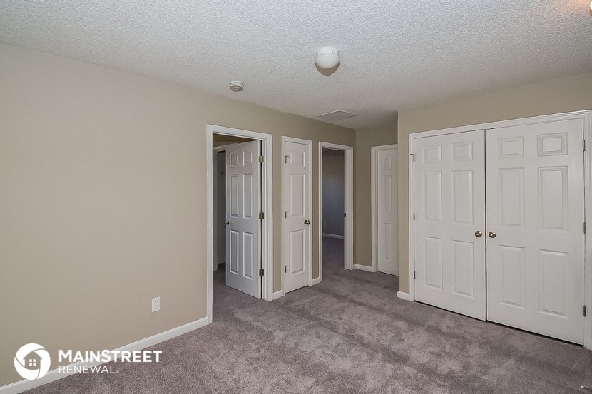 a bedroom with three closets and a carpeted floor