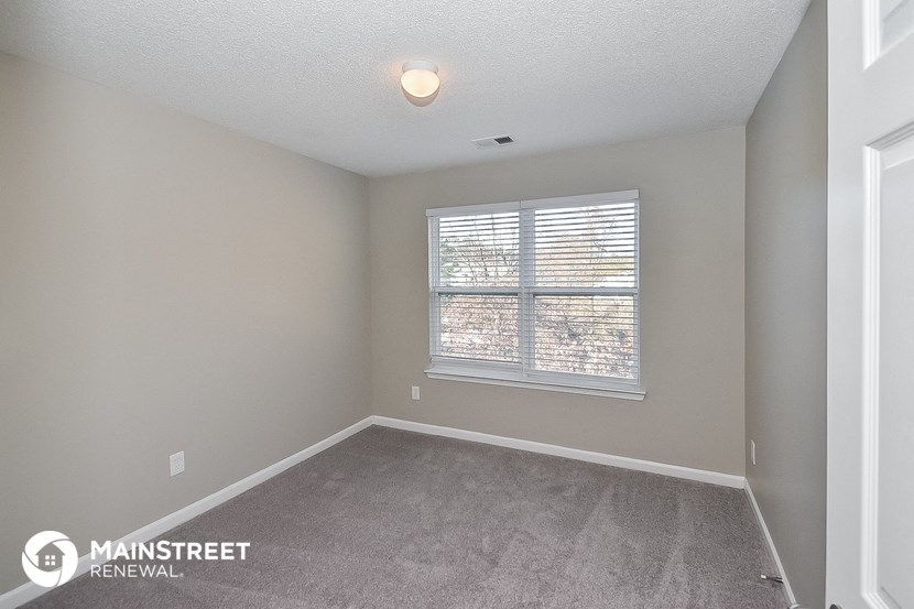 the spacious living room of an apartment with a large window