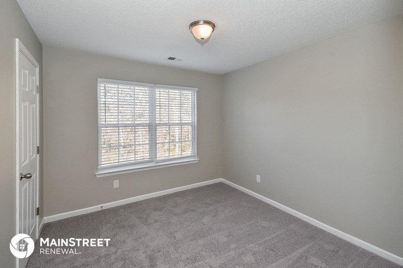 the spacious living room with a large window and carpeted flooring