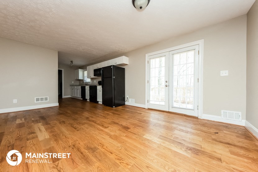 the living room and kitchen of an empty house with wood flooring