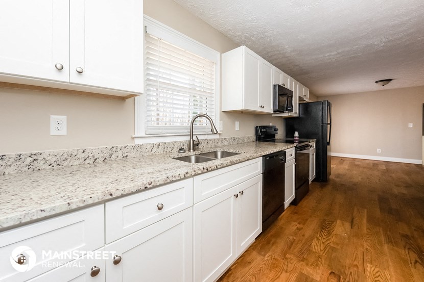 a kitchen with white cabinets and granite counter tops and a sink