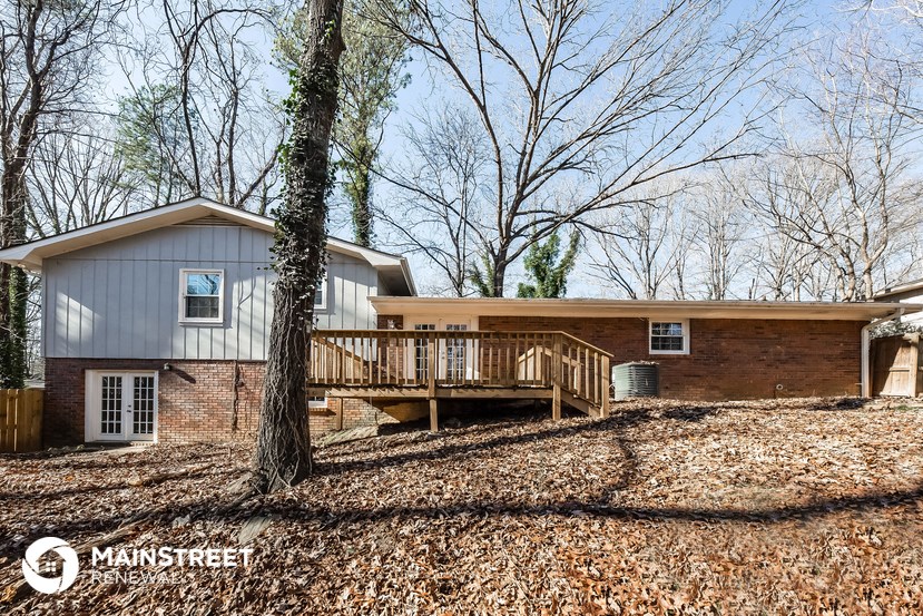 a house with a deck and a tree in front of it