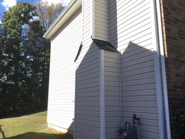 a view of the side of a white house with a window