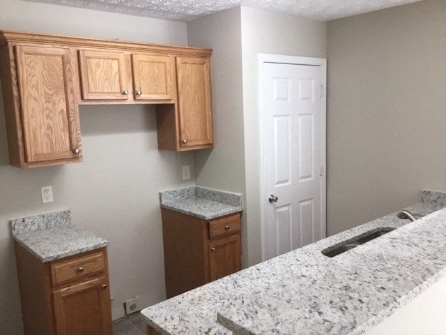 a kitchen with granite counter tops and wooden cabinets