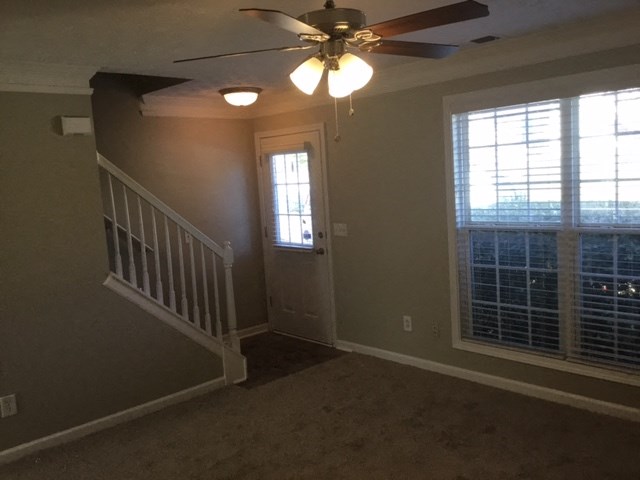 a living room with a staircase and a ceiling fan