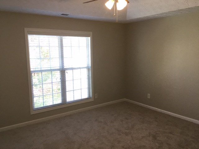 a bedroom with a window and a carpeted floor