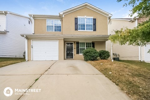 a beige house with a driveway and a white garage door