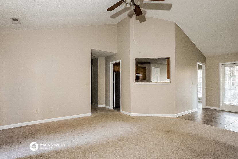 an empty living room with a ceiling fan