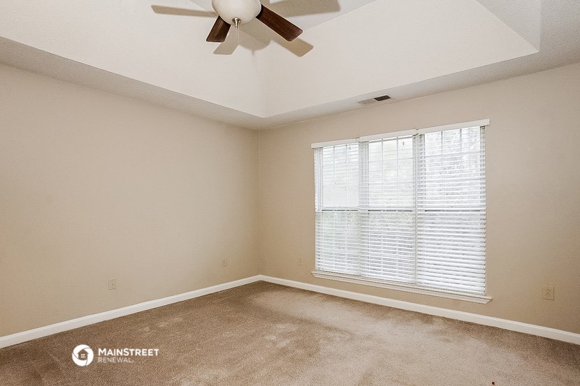 an empty room with a ceiling fan and a window